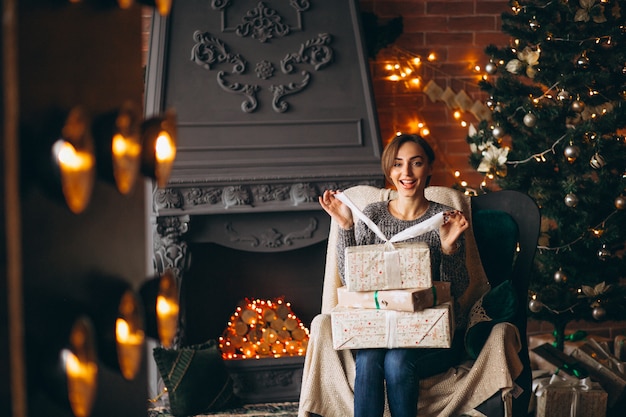 Frau, die im Stuhl durch Weihnachtsbaum sitzt