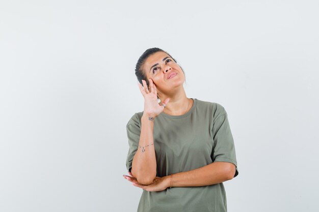 Frau, die im T-Shirt aufschaut und nachdenklich schaut.