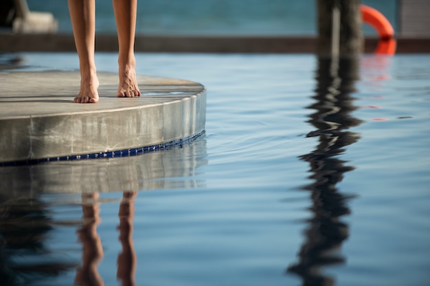 Frau, die im Urlaub am Pool spazieren geht