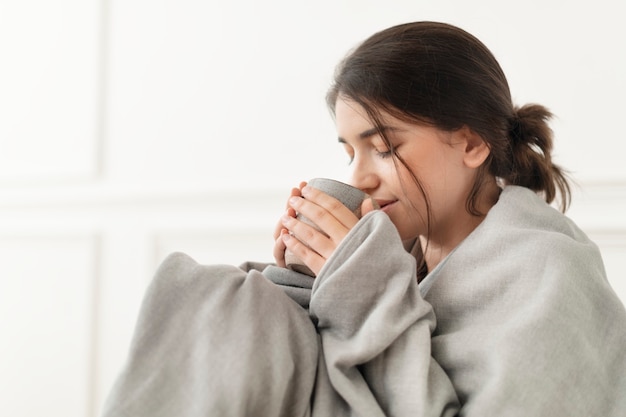 Frau, die im Winter einen Schluck Tee aus der Tasse trinkt