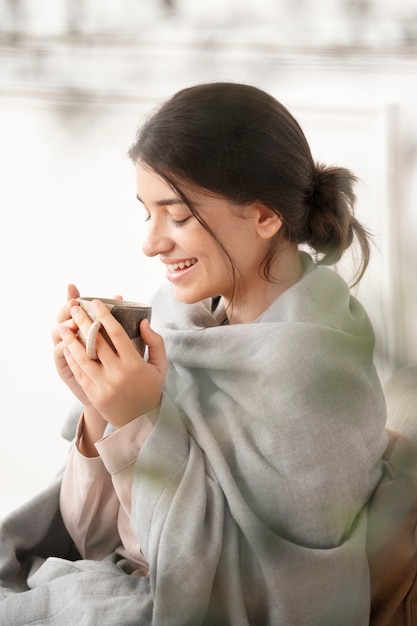 Frau, die im Winter einen Schluck Tee aus der Tasse trinkt