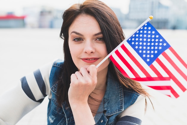 Frau, die in der Hand amerikanische Flagge lächelt und hält