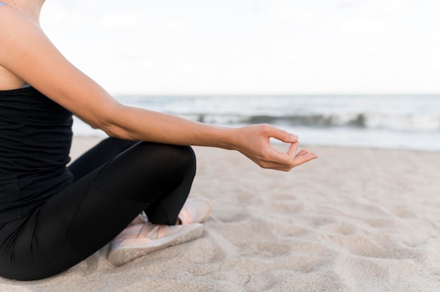Frau, die in der Lotussitzposition auf dem Sand meditiert