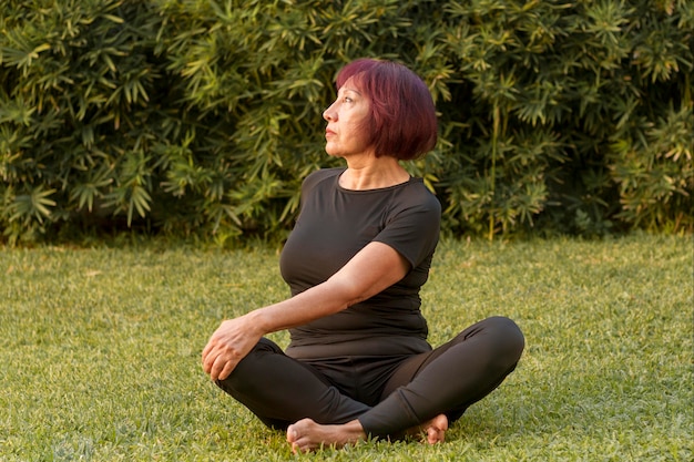 Kostenloses Foto frau, die in der yoga-position sitzt und rückenübungen macht