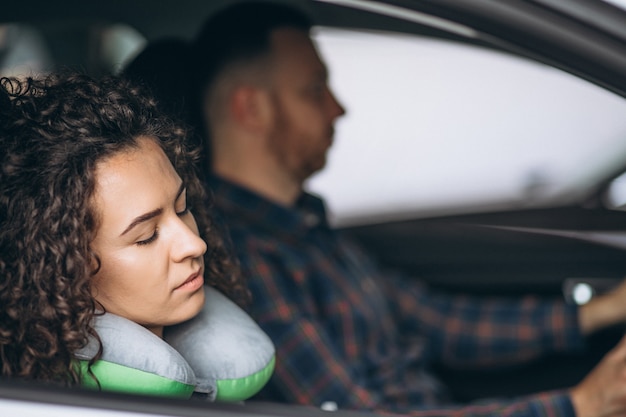 Frau, die in einem auto auf einem autokissen schläft