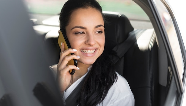 Frau, die in einem Auto sitzt und am Telefon spricht