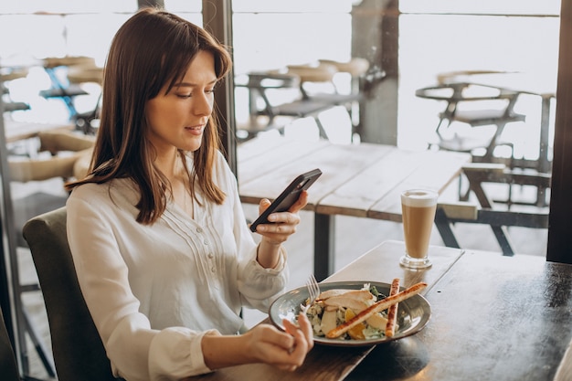 Frau, die in einem Café zu Mittag isst und Salat isst