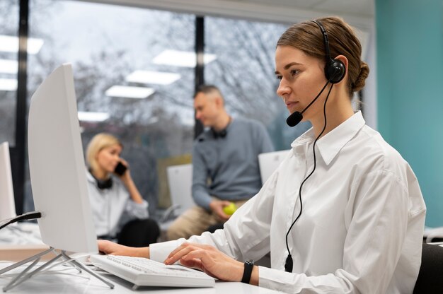 Frau, die in einem Callcenter arbeitet und mit Kunden über Kopfhörer und Mikrofon spricht