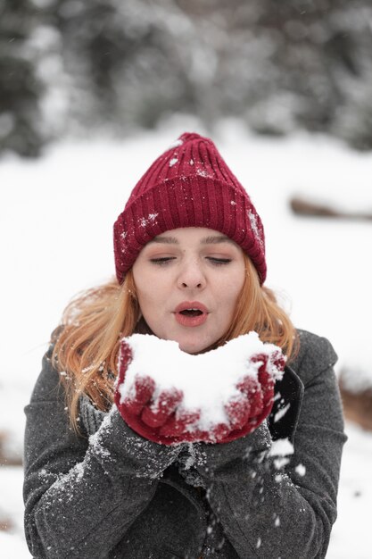 Frau, die in einem Schneehaufen bläst