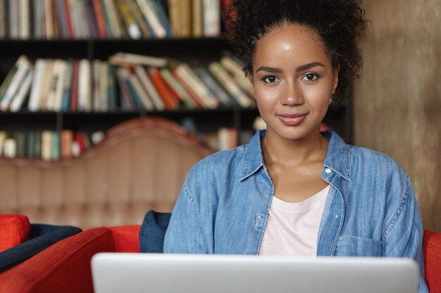 Frau, die in einer Bibliothek mit ihrem Laptop sitzt