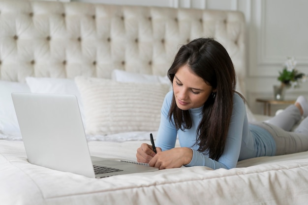 Kostenloses Foto frau, die in ihrem bett bleibt, während sie einen videoanruf auf ihrem laptop hat