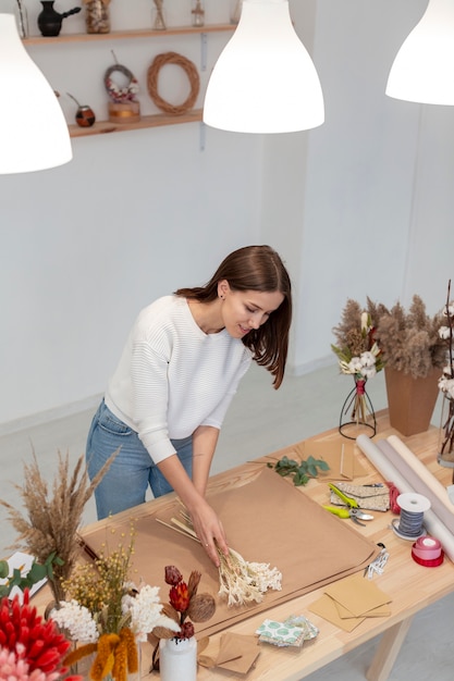 Kostenloses Foto frau, die in ihrem eigenen blumenladen arbeitet