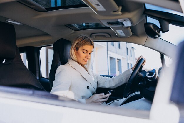 Frau, die innerhalb des Elektroautos bei der Aufladung sitzt