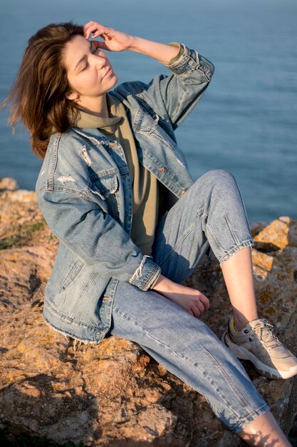 Frau, die Jeansjacke neben Meer trägt