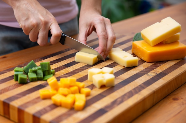 Frau, die Käse auf Würfel mit Messer schneidet