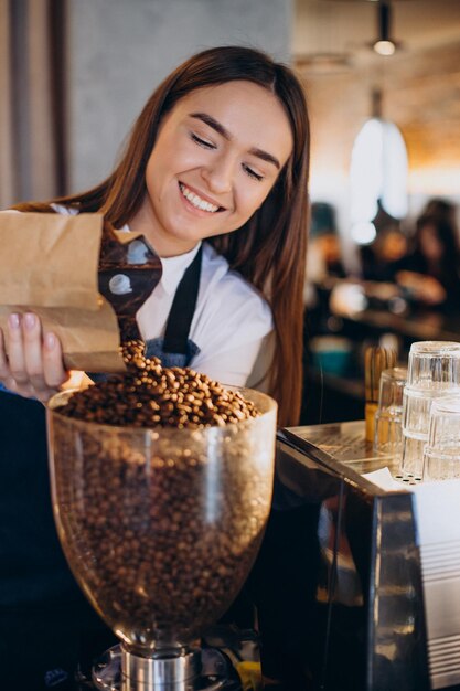 Frau, die Kaffee in der Kaffeemaschine mahlt