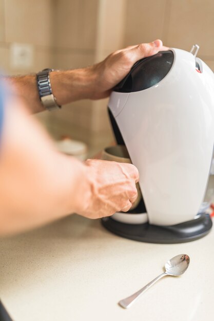 Frau, die Kaffee von der Kapselespresso-Kaffeemaschine herstellt