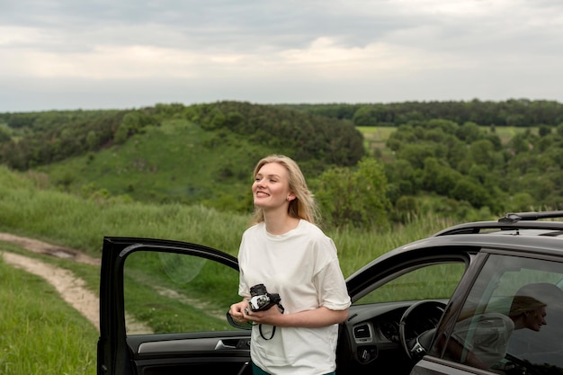 Frau, die Kamera in der Natur mit Auto hält