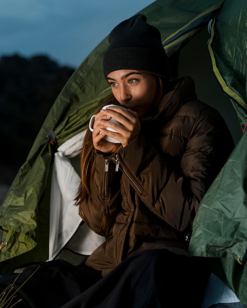 Kostenloses Foto frau, die kampiert und eine tasse tee trinkt