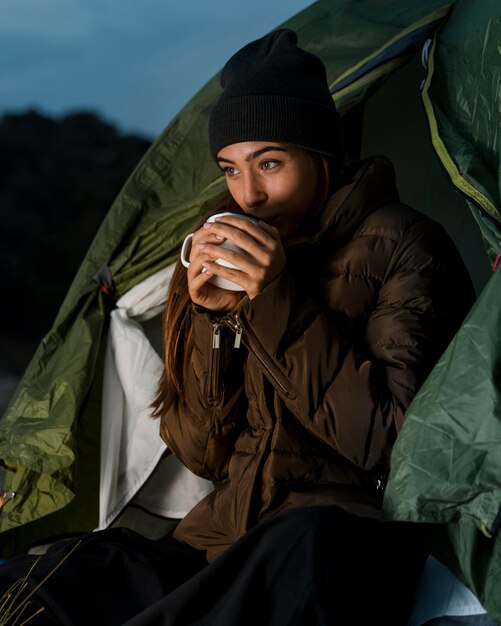 Frau, die kampiert und eine Tasse Tee trinkt