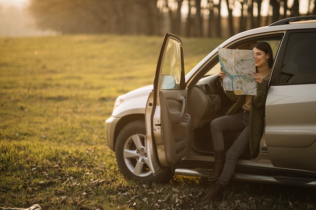 Frau, die Karte im vollen Schuss des Autos hält