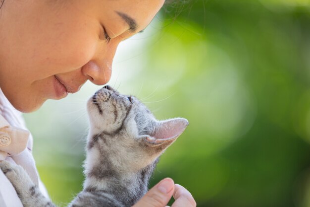 Frau, die Katze im Garten umarmt