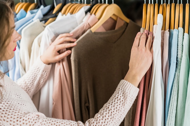 Frau, die Kleid während des Einkaufens am Kleiderkleid wählt