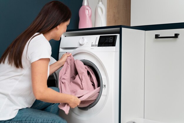 Frau, die Kleidung aus der Waschmaschine nimmt