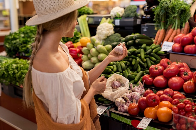 Kostenloses Foto frau, die knoblauch vom marktplatz kauft