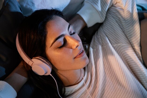 Frau, die Kopfhörer für Musik zu Hause im Bett verwendet