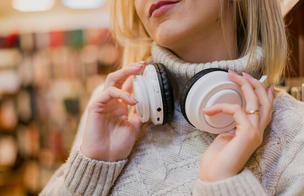 Frau, die Kopfhörer um den Hals in der Buchhandlung hält