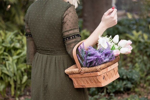 Frau, die Korb mit Blumen hält