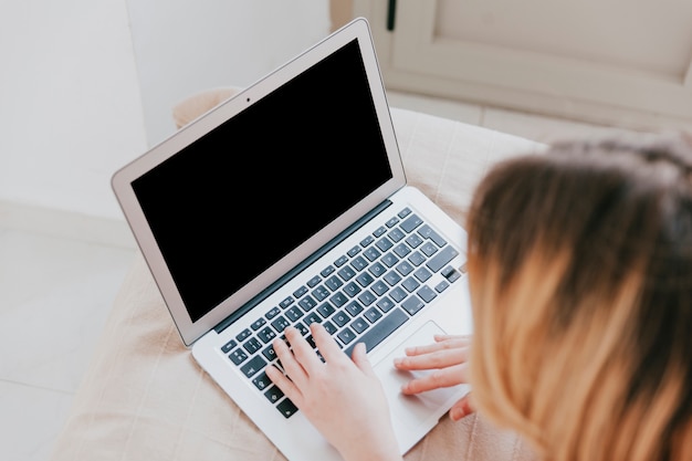 Frau, die Laptop auf Bett verwendet