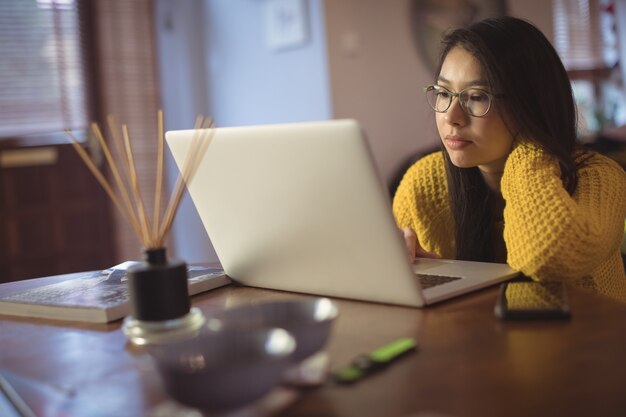 Frau, die Laptop auf Tisch betrachtet