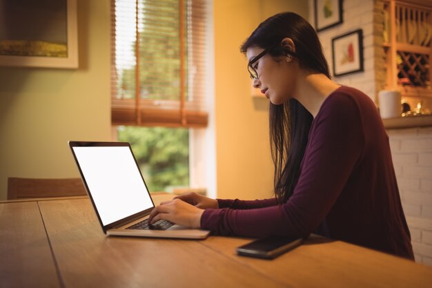 Frau, die Laptop auf Tisch im Wohnzimmer verwendet