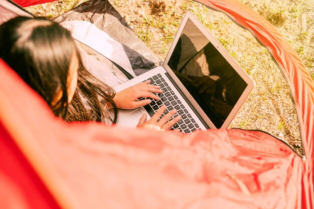 Frau, die Laptop beim Stillstehen beim Kampieren verwendet