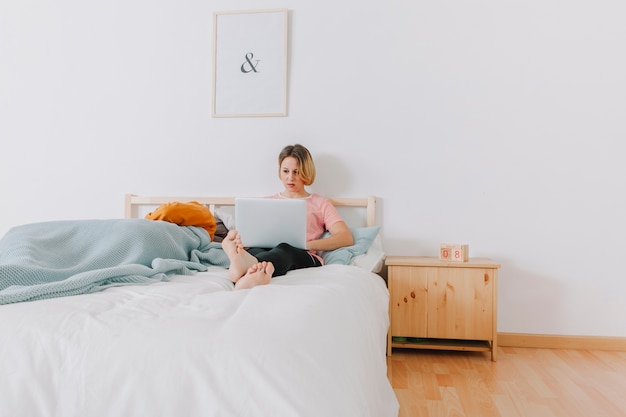 Frau, die Laptop im Bett verwendet