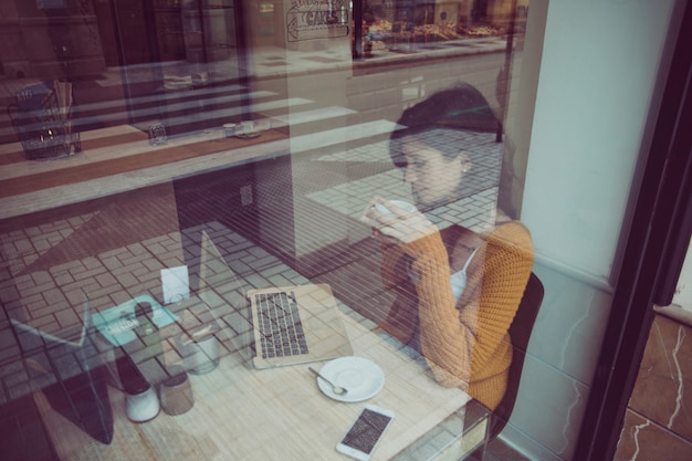 Frau, die Laptop im Café trinkt und verwendet