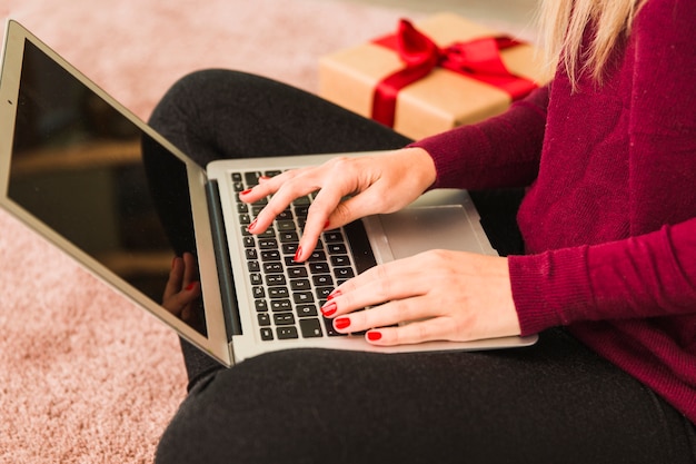 Frau, die Laptop nahe Geschenkbox verwendet