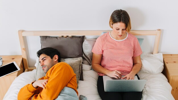 Frau, die Laptop nahe traurigem Mann verwendet