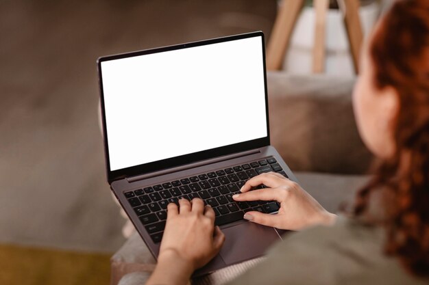 Frau, die Laptop zu Hause auf der Couch benutzt