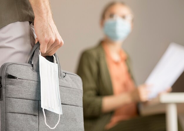 Frau, die Laptoptasche und Gesichtsmaske trägt