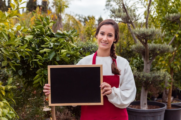 Frau, die leere Tafel im Garten hält