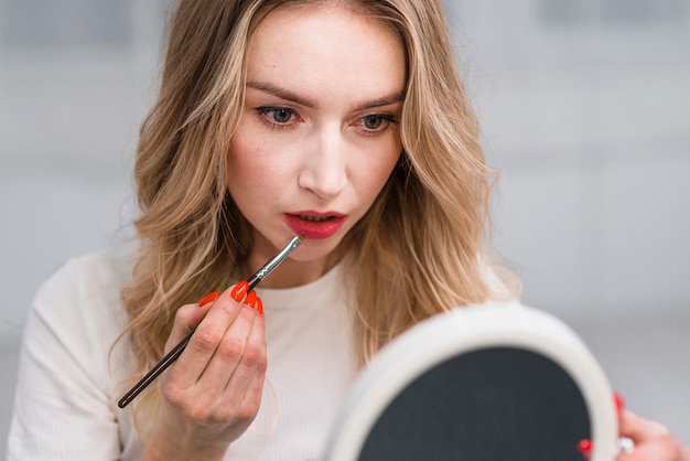 Kostenloses Foto frau, die lippenverfassung mit spiegel tut