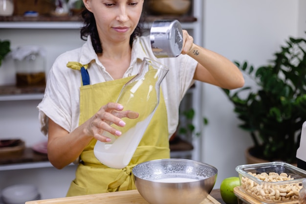 Frau, die Mandelmilch in Glasflasche gießt