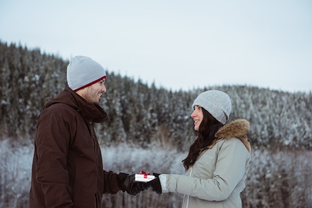 Frau, die Mann auf schneebedecktem Berg Geschenk gibt