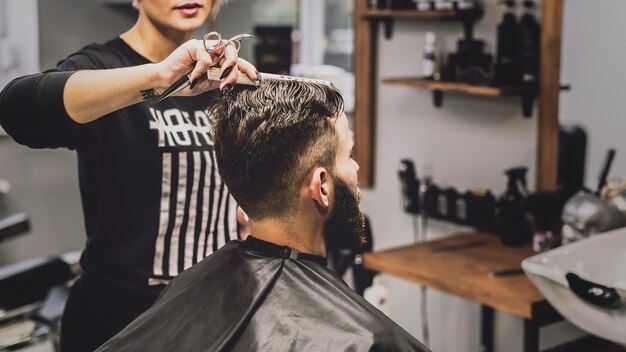 Frau, die Mann kämmt und haircutting ist