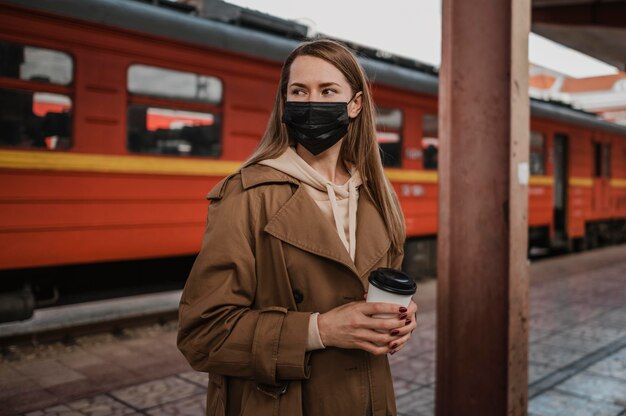 Frau, die medizinische Maske in einem Bahnhof trägt