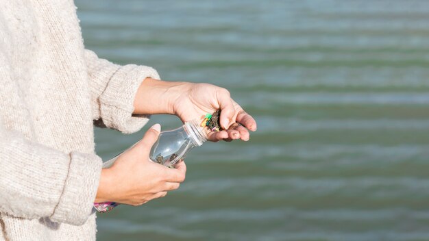 Frau, die Meer von Plastikflasche reinigt