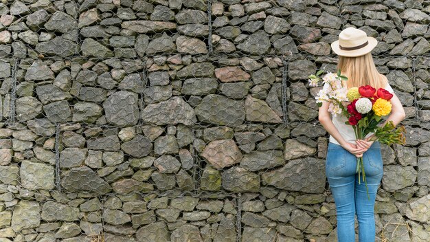 Frau, die mit Blumen hinten zurück steht